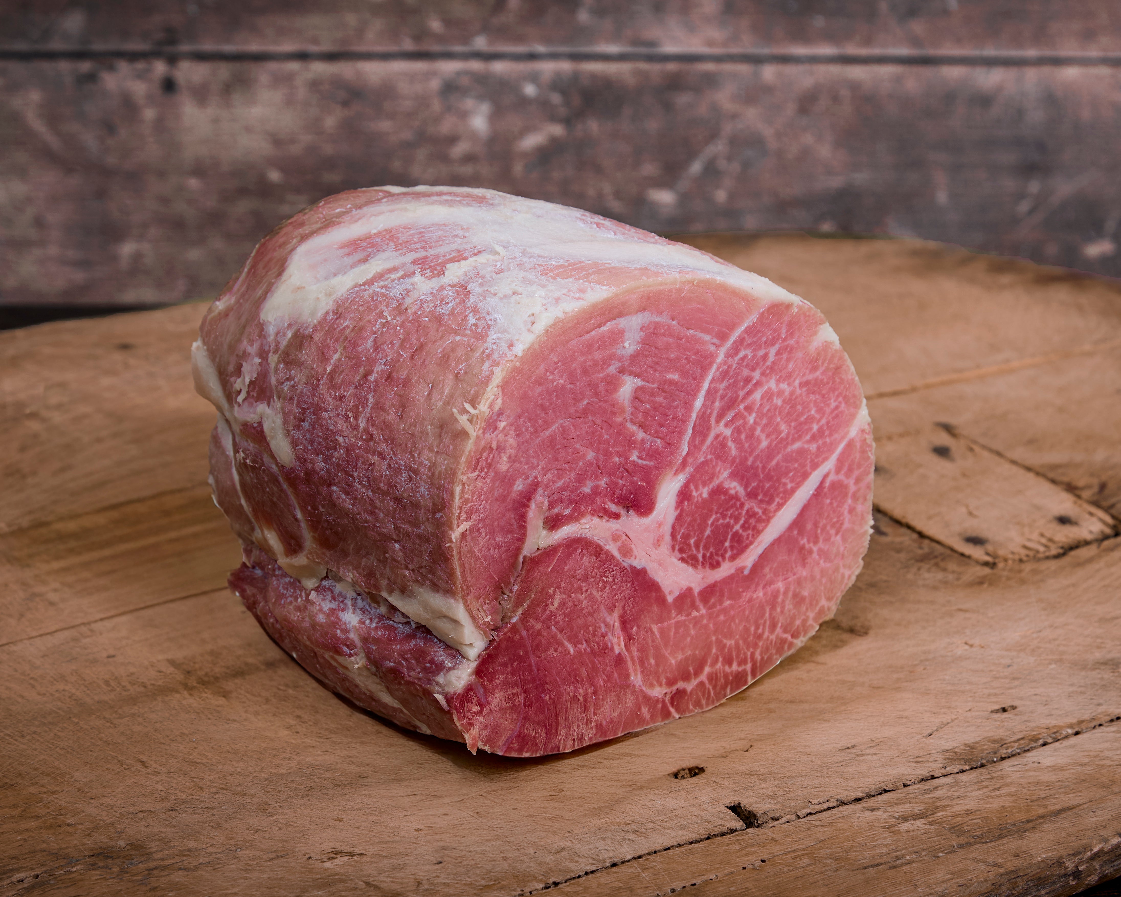 Half of a cured and cooked Turner Ham on a wooden cutting board