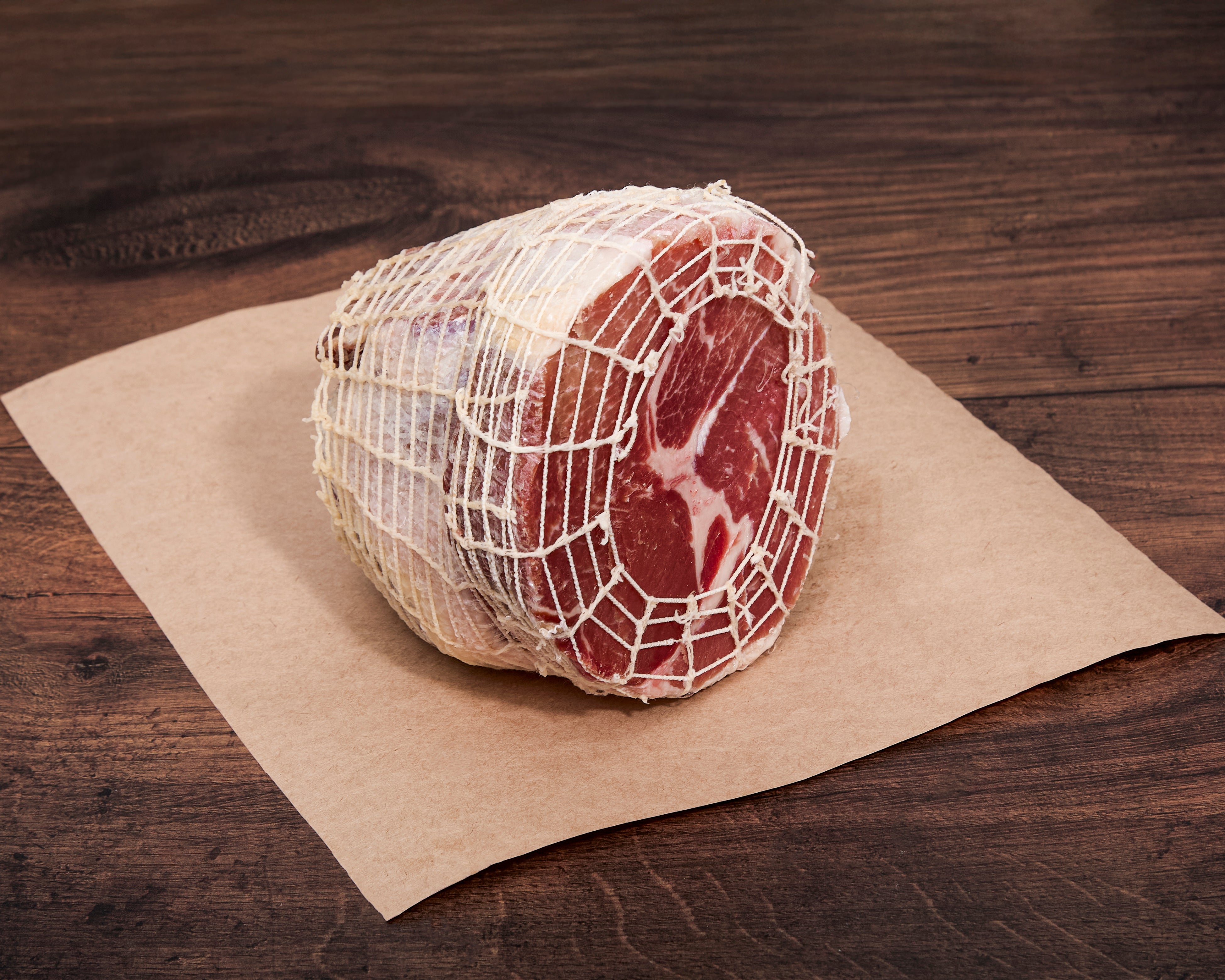 Half of an uncooked Turner Ham in netting on brown butcher paper