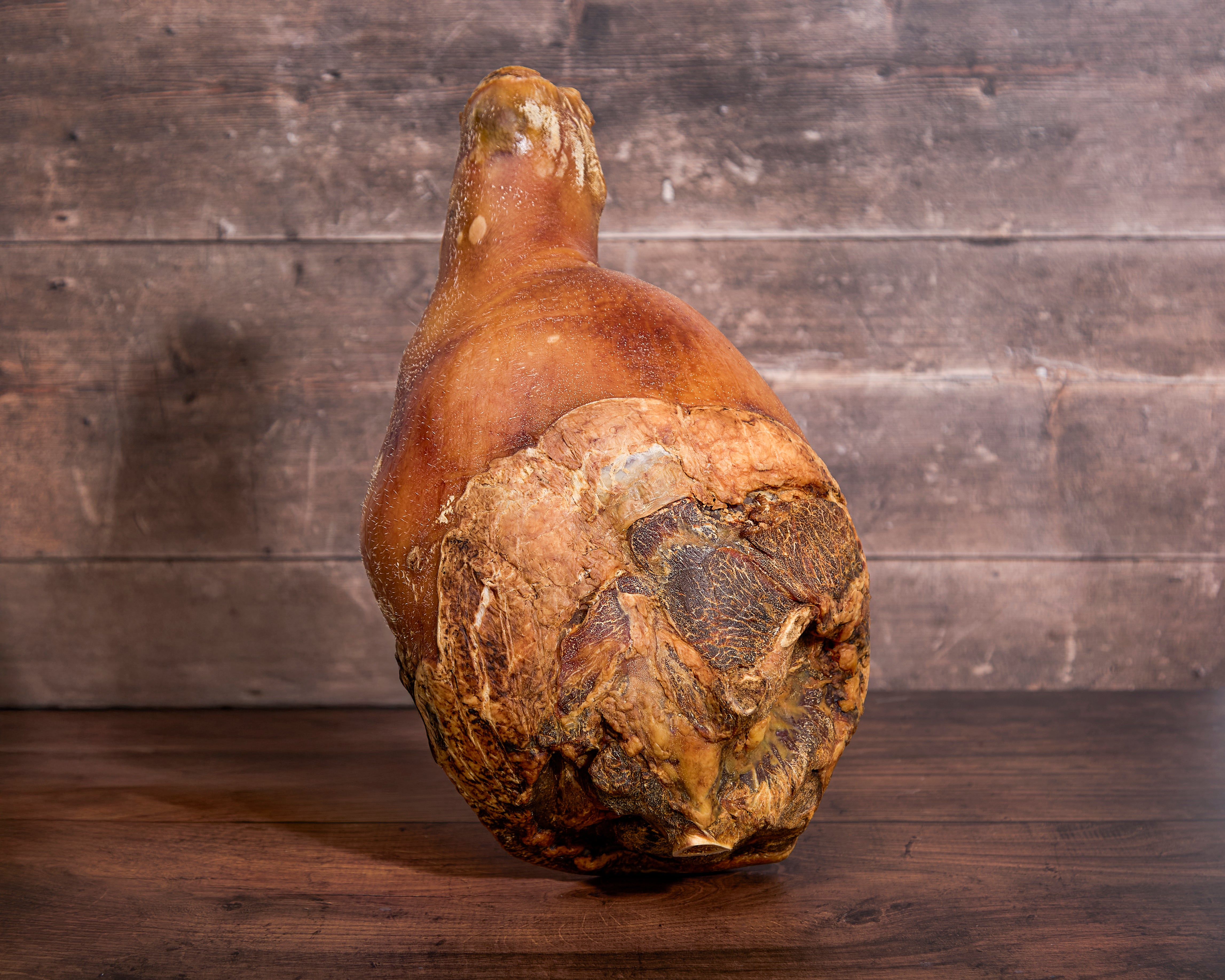 Whole uncooked bone-in Turner Ham displayed in front of a wooden background