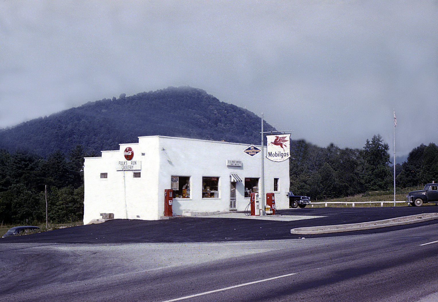 White building with signs on a road with mountains in the background