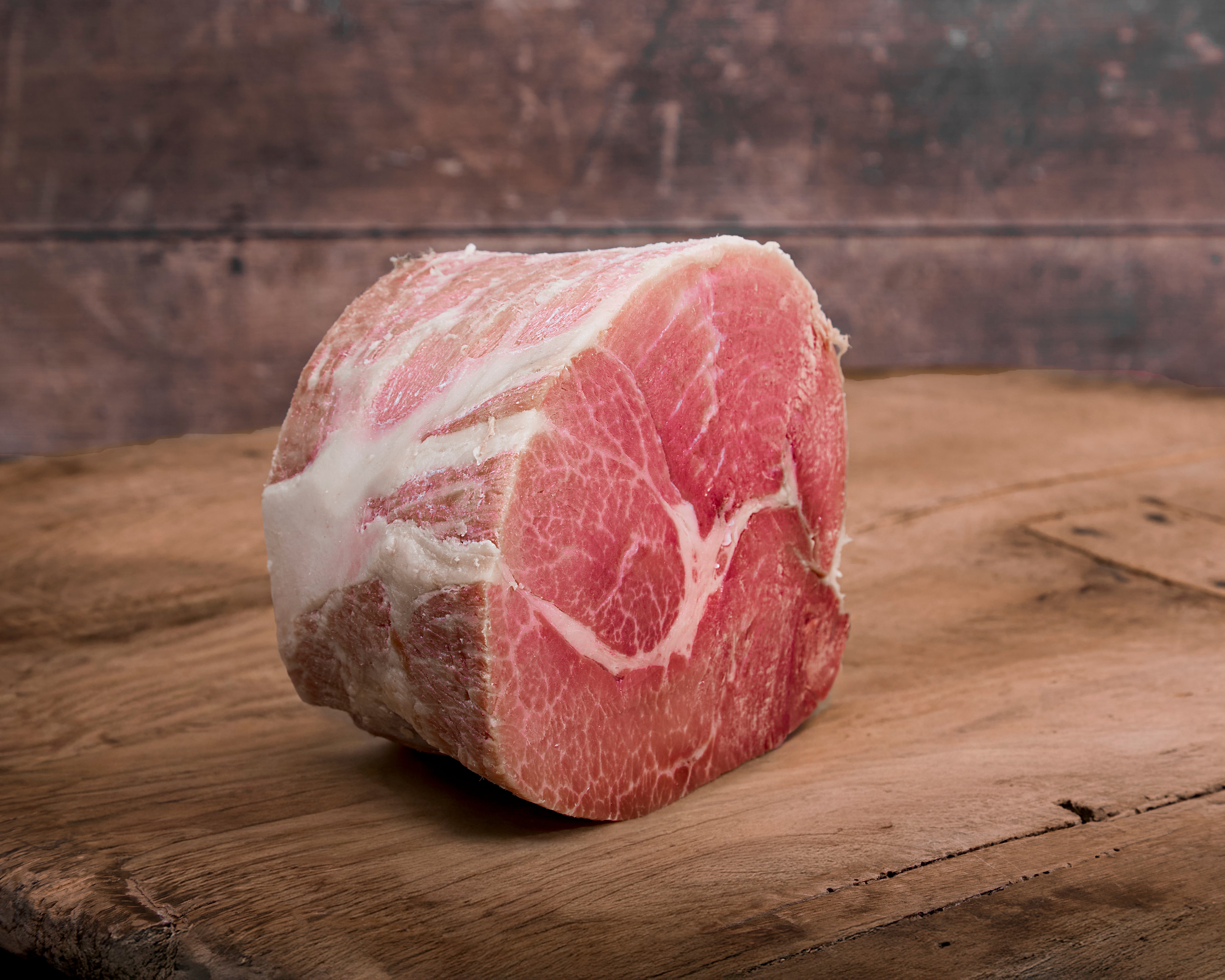A cut of cooked and cured Turner Ham on a wooden cutting board